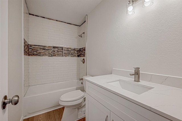 full bathroom featuring vanity, hardwood / wood-style flooring, tiled shower / bath combo, and toilet