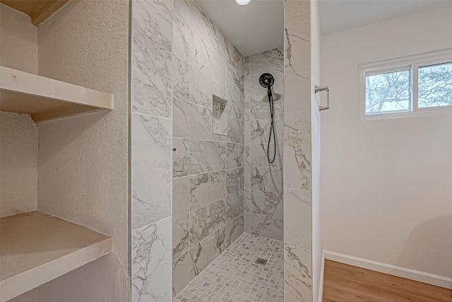 bathroom with hardwood / wood-style flooring and a tile shower