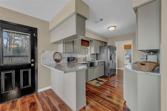 kitchen with gray cabinetry, light hardwood / wood-style flooring, kitchen peninsula, and stainless steel refrigerator with ice dispenser