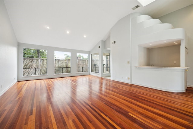 unfurnished living room featuring a wealth of natural light, high vaulted ceiling, and wood-type flooring