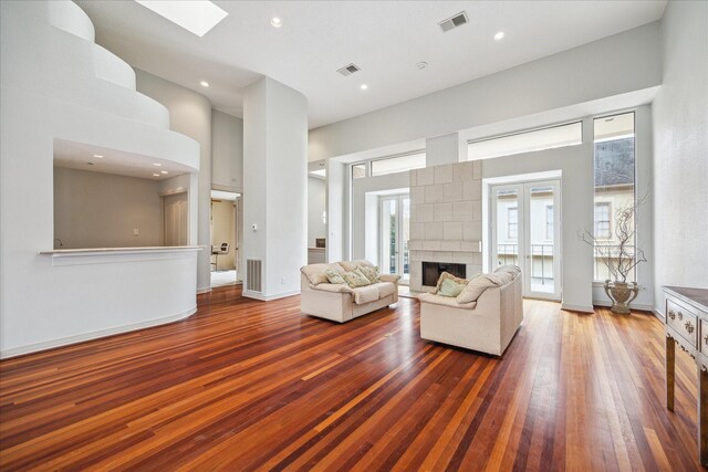 5614 San Felipe St Unit G, Houston, TX 77056 - living room featuring wood-type flooring, a high ceiling, a tile fireplace, a skylight, and recessed lighting