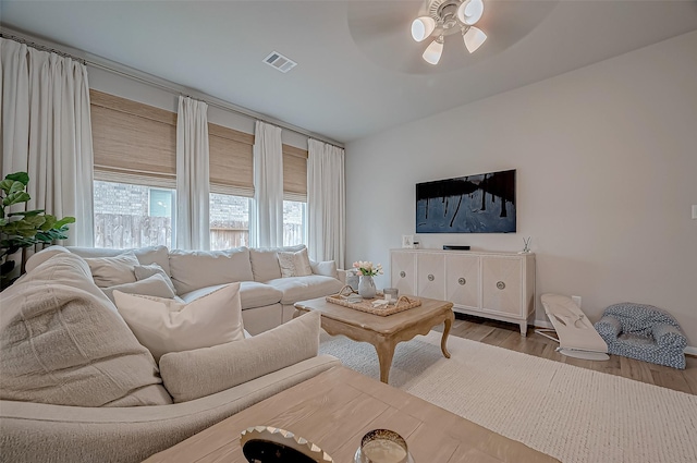 living room with ceiling fan, visible vents, and wood finished floors