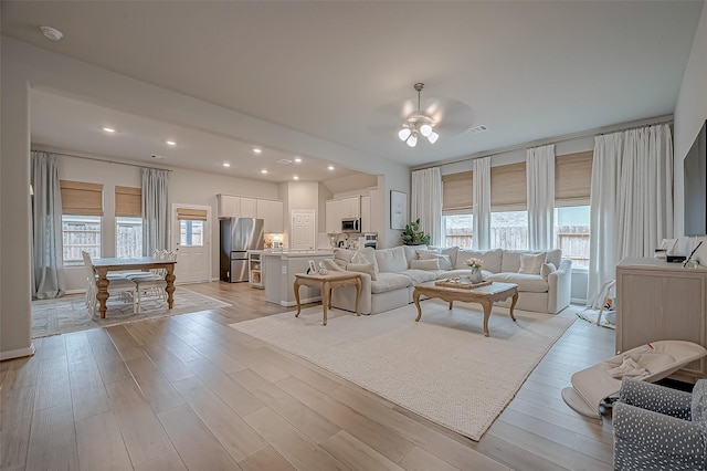 living area with light wood-type flooring, a ceiling fan, visible vents, and recessed lighting