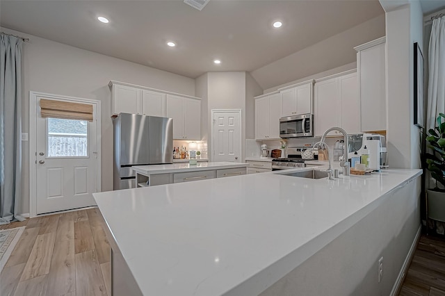 kitchen with light countertops, white cabinets, stainless steel appliances, and light wood-style flooring