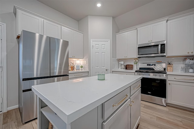 kitchen with light countertops, a kitchen island, backsplash, and stainless steel appliances