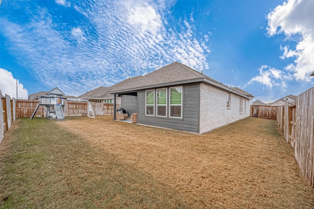 back of property featuring a playground, a lawn, and a fenced backyard