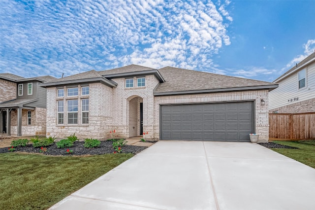 view of front of property with fence, a garage, brick siding, and stone siding