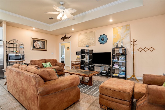 living room with ceiling fan, light tile patterned floors, a tray ceiling, and ornamental molding