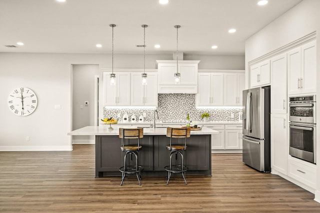 kitchen with pendant lighting, white cabinetry, an island with sink, and appliances with stainless steel finishes