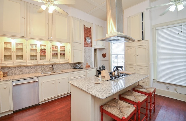 kitchen with island exhaust hood, stainless steel appliances, light stone countertops, and sink