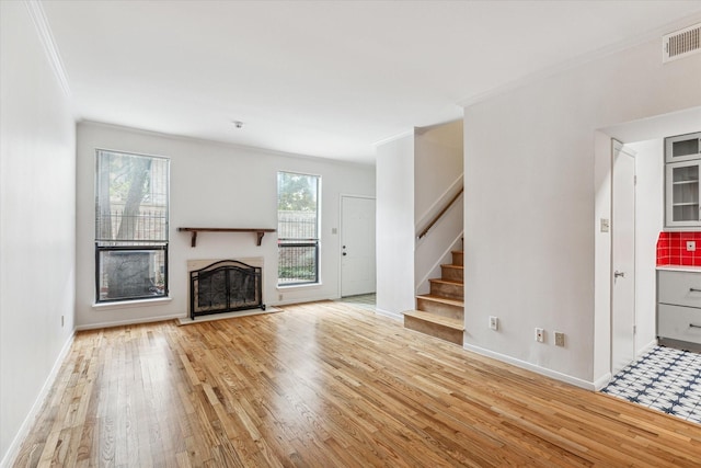 unfurnished living room featuring ornamental molding and light wood-type flooring