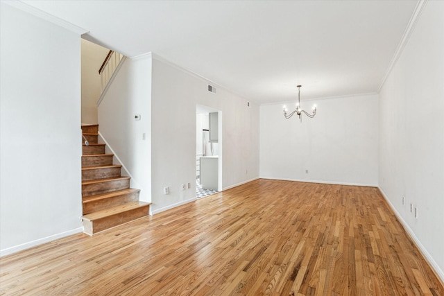 spare room with crown molding, an inviting chandelier, and light hardwood / wood-style floors