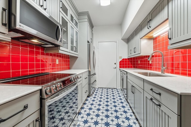 kitchen with tasteful backsplash, stainless steel appliances, sink, and gray cabinetry