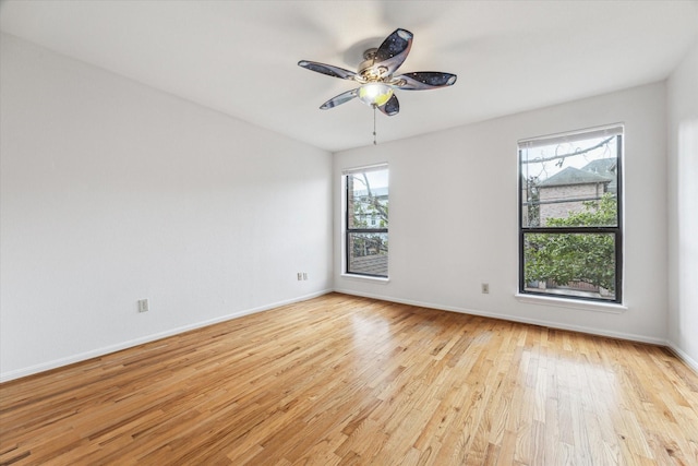 spare room featuring a ceiling fan, light wood-style flooring, and baseboards