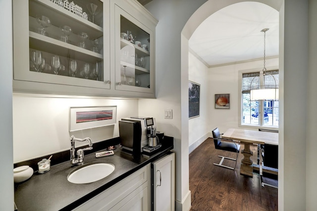 bar featuring hanging light fixtures, sink, dark wood-type flooring, and white cabinets