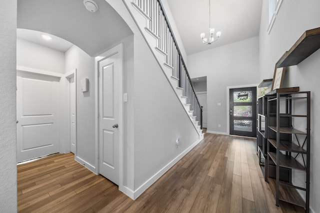 entrance foyer featuring hardwood / wood-style flooring, a towering ceiling, and a chandelier