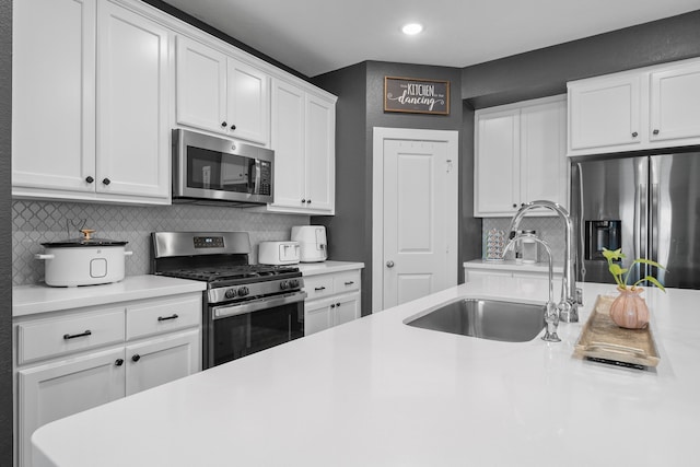 kitchen with tasteful backsplash, appliances with stainless steel finishes, sink, and white cabinets