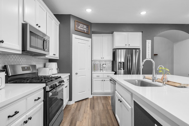 kitchen featuring sink, white cabinetry, stainless steel appliances, tasteful backsplash, and wood-type flooring