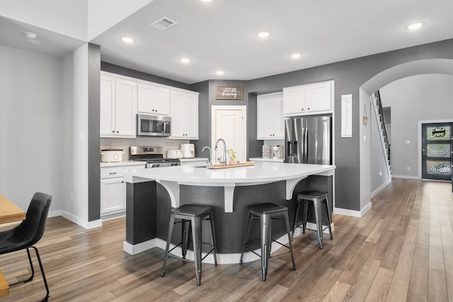 kitchen featuring a kitchen island with sink, white cabinets, and appliances with stainless steel finishes