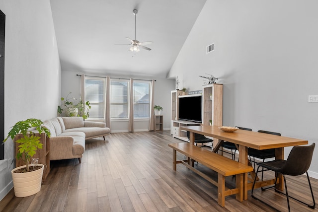 dining room with ceiling fan, high vaulted ceiling, and hardwood / wood-style floors