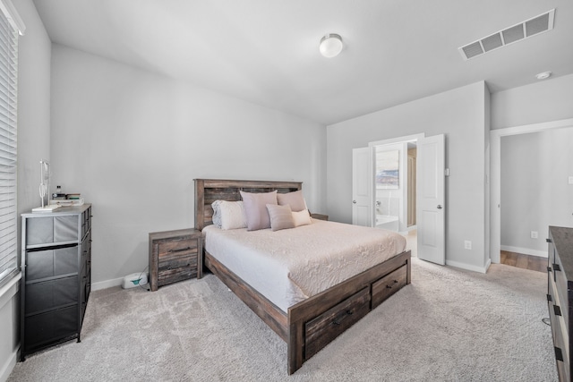 bedroom with connected bathroom and light carpet