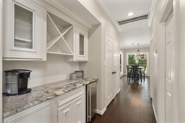 bar featuring dark wood-type flooring, ornamental molding, beverage cooler, and white cabinets