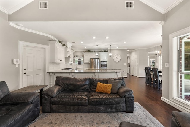 living room featuring lofted ceiling, sink, crown molding, dark hardwood / wood-style floors, and a chandelier