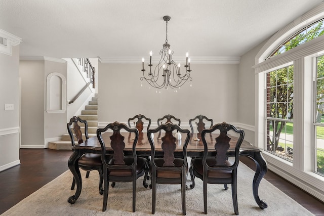 dining room featuring dark hardwood / wood-style flooring, ornamental molding, a textured ceiling, and an inviting chandelier