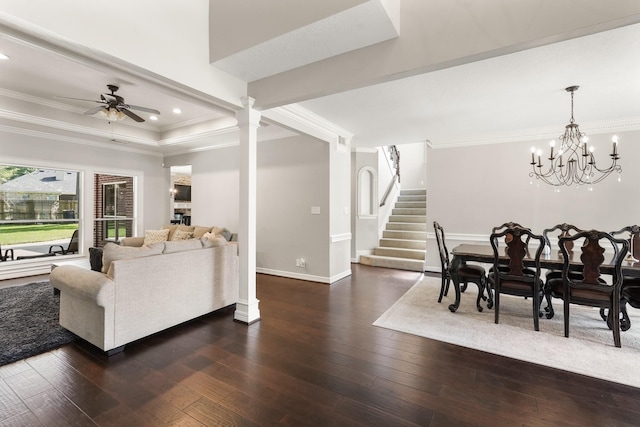 living room with crown molding, dark hardwood / wood-style flooring, ceiling fan with notable chandelier, a raised ceiling, and ornate columns