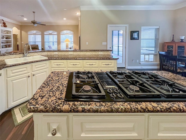 kitchen featuring sink, white cabinetry, crown molding, dark stone countertops, and gas cooktop