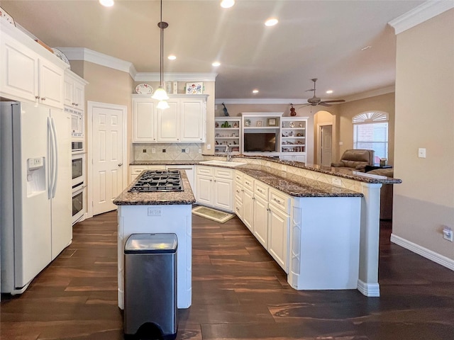 kitchen with white appliances, white cabinetry, a center island, decorative light fixtures, and kitchen peninsula