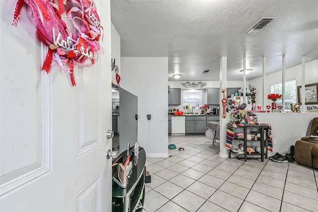 kitchen featuring gray cabinets, light tile patterned flooring, a textured ceiling, and white dishwasher