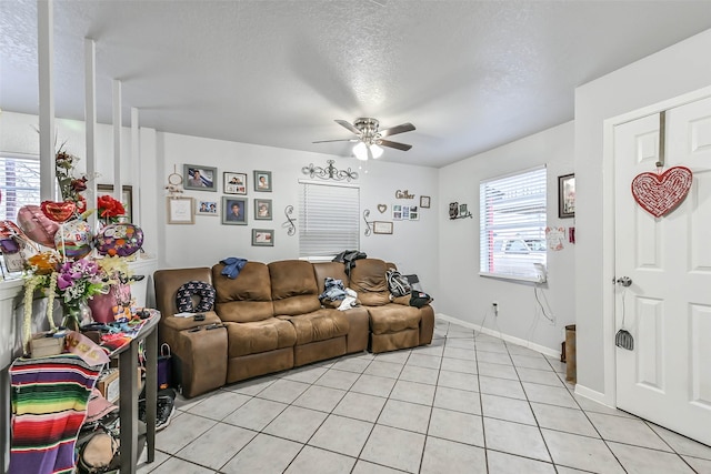 living room with light tile patterned flooring, ceiling fan, and a textured ceiling