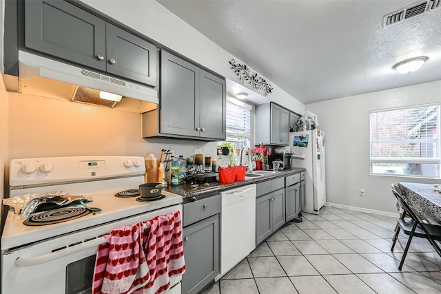 kitchen featuring gray cabinets, light tile patterned flooring, sink, white appliances, and a textured ceiling