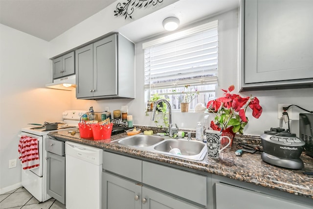 kitchen featuring sink, gray cabinetry, dark stone countertops, light tile patterned floors, and white appliances