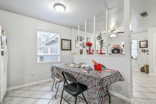 tiled dining area with a textured ceiling and ceiling fan