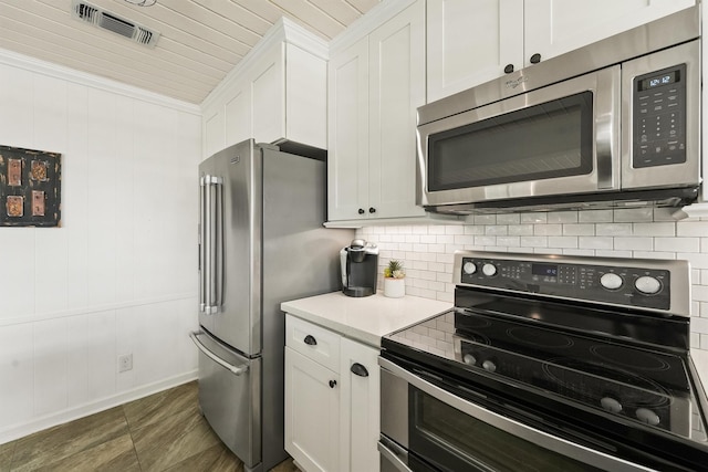 kitchen with white cabinetry, backsplash, ornamental molding, and stainless steel appliances