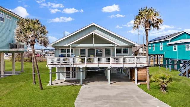 rear view of house featuring a carport, a wooden deck, and a lawn