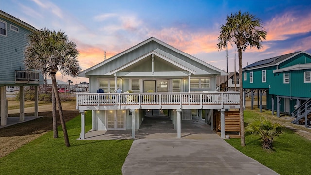 back house at dusk with a carport, a deck, and a lawn