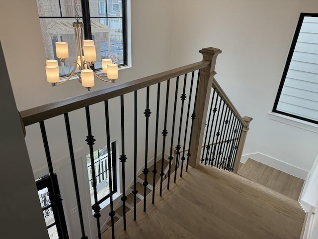 stairway with a chandelier and hardwood / wood-style floors