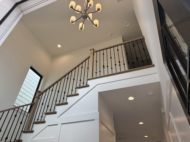 stairway with a high ceiling and a notable chandelier