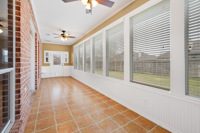 unfurnished sunroom featuring ceiling fan