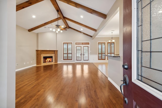 unfurnished living room with hardwood / wood-style flooring, beam ceiling, high vaulted ceiling, a high end fireplace, and ceiling fan with notable chandelier