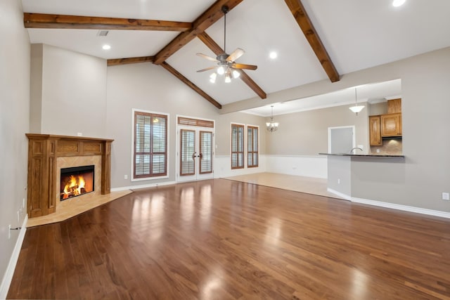 unfurnished living room featuring ceiling fan, hardwood / wood-style floors, beam ceiling, high vaulted ceiling, and a fireplace