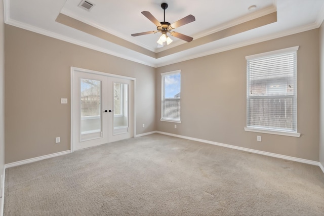 unfurnished room with a raised ceiling, ornamental molding, light carpet, and french doors