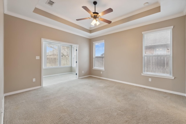 empty room with crown molding, light colored carpet, and a tray ceiling