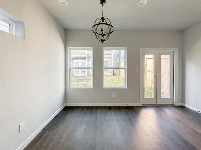 unfurnished dining area featuring french doors, dark hardwood / wood-style floors, and a chandelier