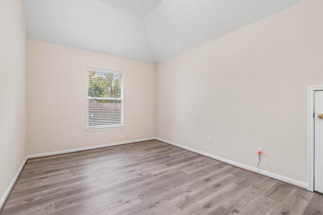 spare room featuring lofted ceiling and light wood-type flooring