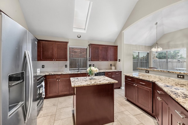 kitchen with stainless steel appliances, vaulted ceiling with skylight, light stone countertops, a kitchen island, and decorative light fixtures