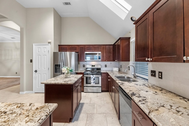 kitchen featuring sink, light stone counters, high vaulted ceiling, appliances with stainless steel finishes, and a kitchen island